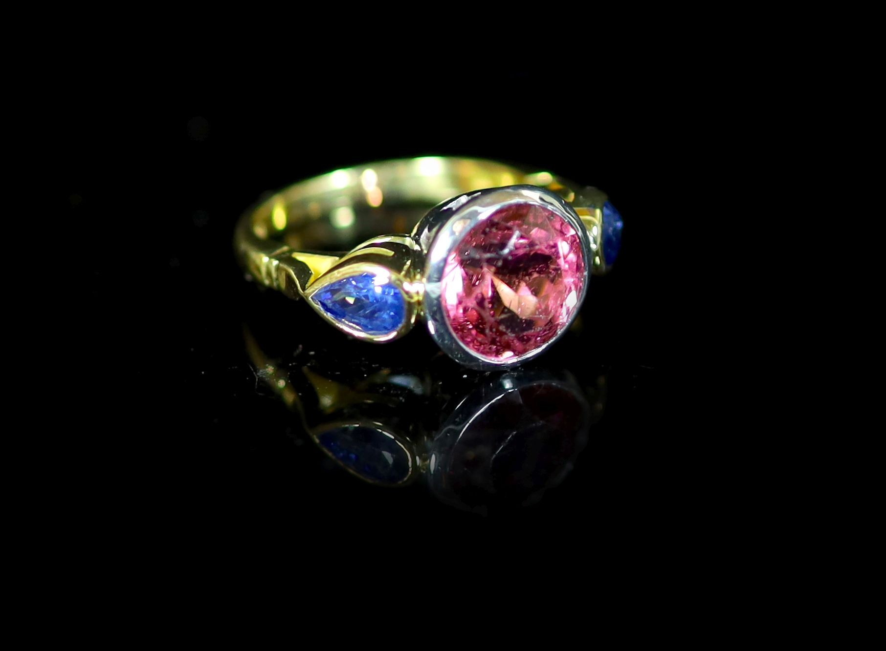 A Theo Fennell 18ct gold, collet set single stone pink tourmaline and two stone pear shaped sapphire set dress ring